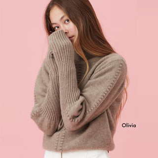 Person wearing a cozy, oversized sweater against a pink background